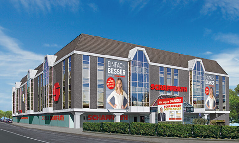 Beschreibung des Bildes gemäß Barrierefreiheitsgesetz: Das Bild zeigt ein großes, modernes Schaffrath-Gebäude mit einer Fassade aus dunklen Paneelen und großen, vertikalen Glasfenstern. Auf der Fassade sind mehrere auffällige Werbeplakate angebracht. Ein großes Plakat zeigt eine blonde Frau in weißem Oberteil mit dem Text „EINFACH BESSER“. Rechts daneben ist der rote Schriftzug „SCHAFFRATH“ auf der Fassade deutlich sichtbar. Im unteren Bereich ist ein weiteres Plakat mit rotem Hintergrund angebracht, auf dem „Wir sagen DANKE!“ steht. Das Gebäude steht an einer Straße, vor der sich ein kleiner Grünstreifen mit niedrigen Büschen befindet. Der Himmel ist strahlend blau mit einigen weißen Wolken, was dem Bild eine freundliche und einladende Atmosphäre verleiht.